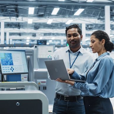 Engineers reviewing data on a laptop in a manufacturing facility
